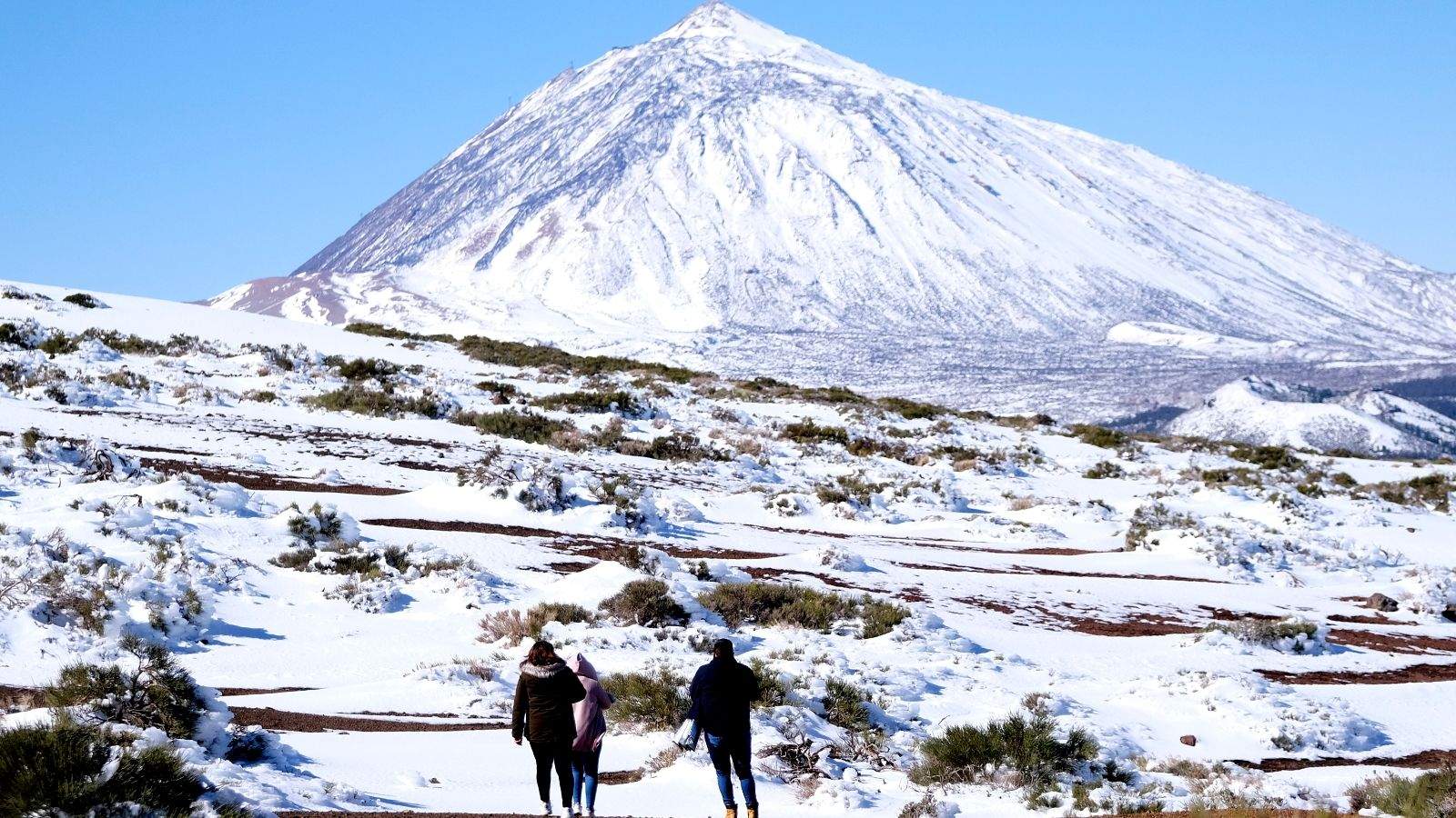 Personas paseando frente al Teide nevado. /Archivo
