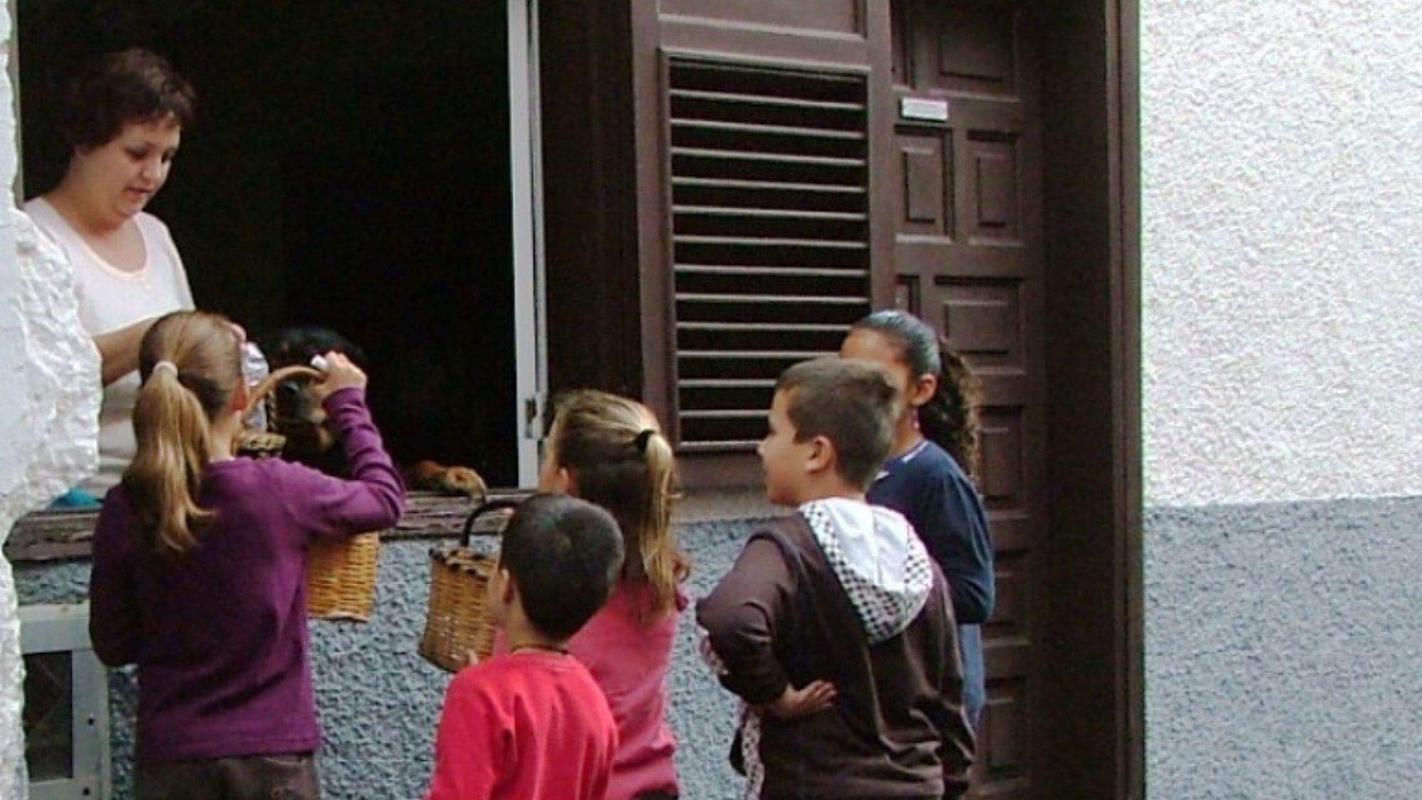 Unos niños se acercan a una vecina con cestas de mimbre en la celebración de Los Santitos. / Cedida