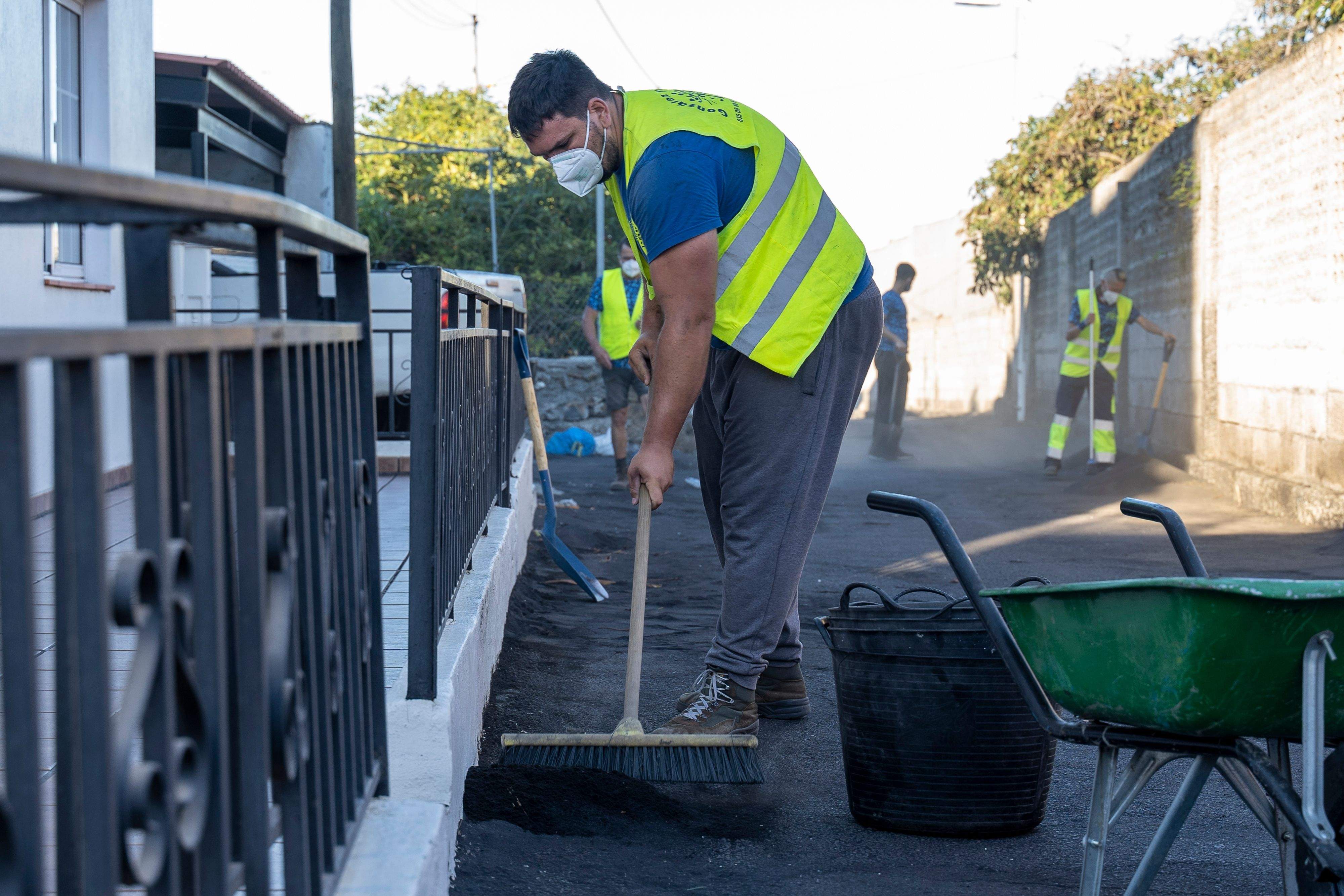 Una persona limpia la ceniza acumulada por el volcán en La Palma. / Europa Press