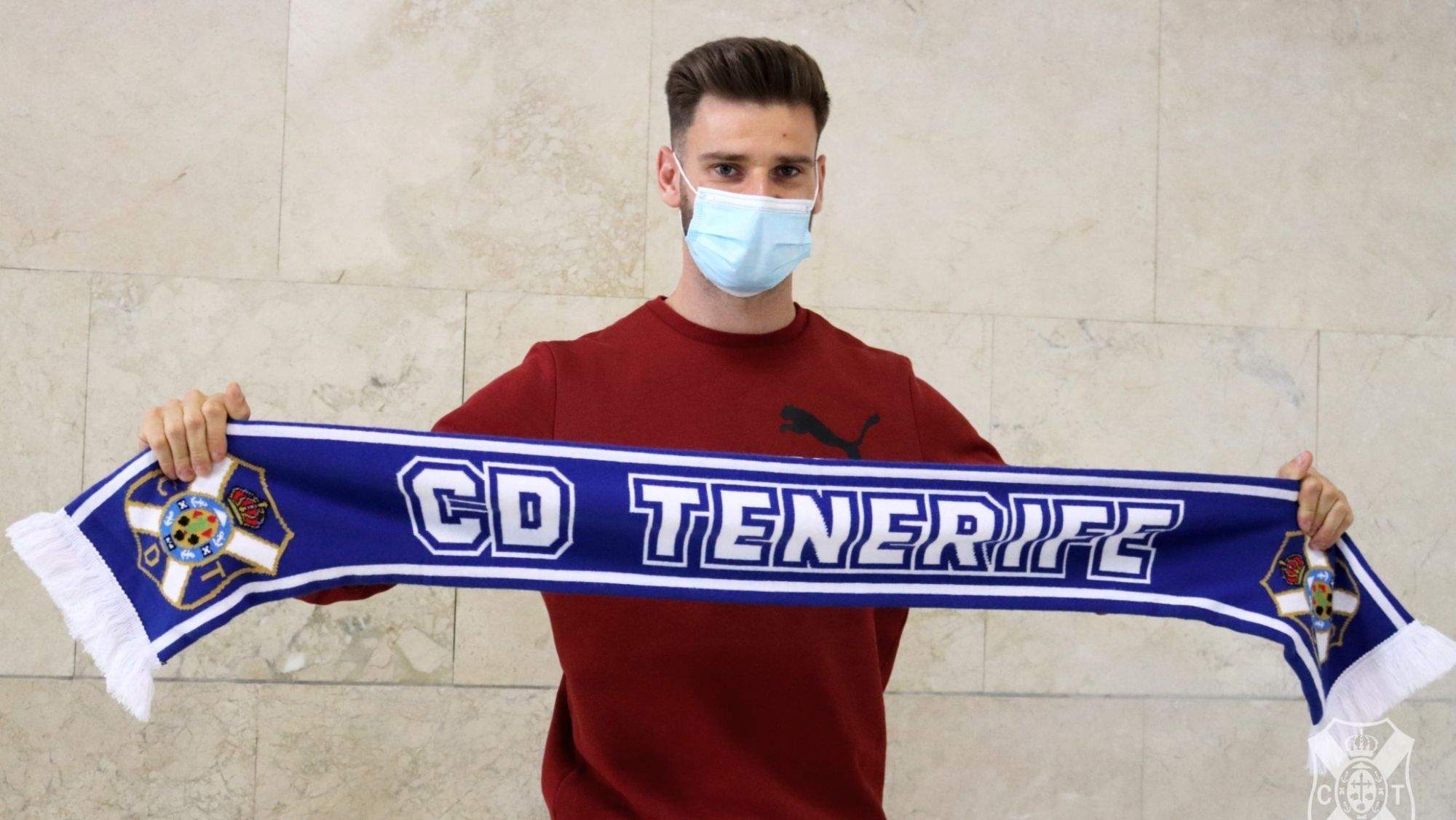 Mario González posa con una bufanda del CD Tenerife a su llegada a la isla. / CD Tenerife