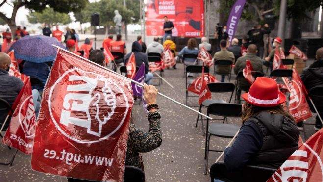 Una mujer se resguarda de la lluvia con una bandera de UGT durante la asamblea conjunta celebrada este martes por CCOO y UGT para explicar la reforma laboral./ EFE - Miguel Barreto Una mujer se resguarda de la lluvia con una bandera de UGT durante la asamblea conjunta celebrada este martes por CCOO y UGT para explicar la reforma laboral./ EFE - Miguel Barreto