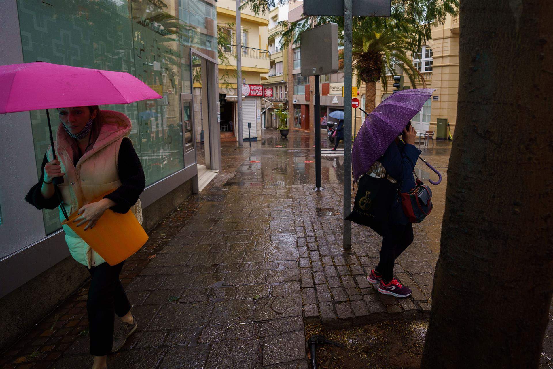 Viandantes en Santa Cruz de Tenerife protegiéndose con el paraguas de la lluvia que acompaña a la borrasca Celia./ EFE/Ramón de la Rocha Canarias