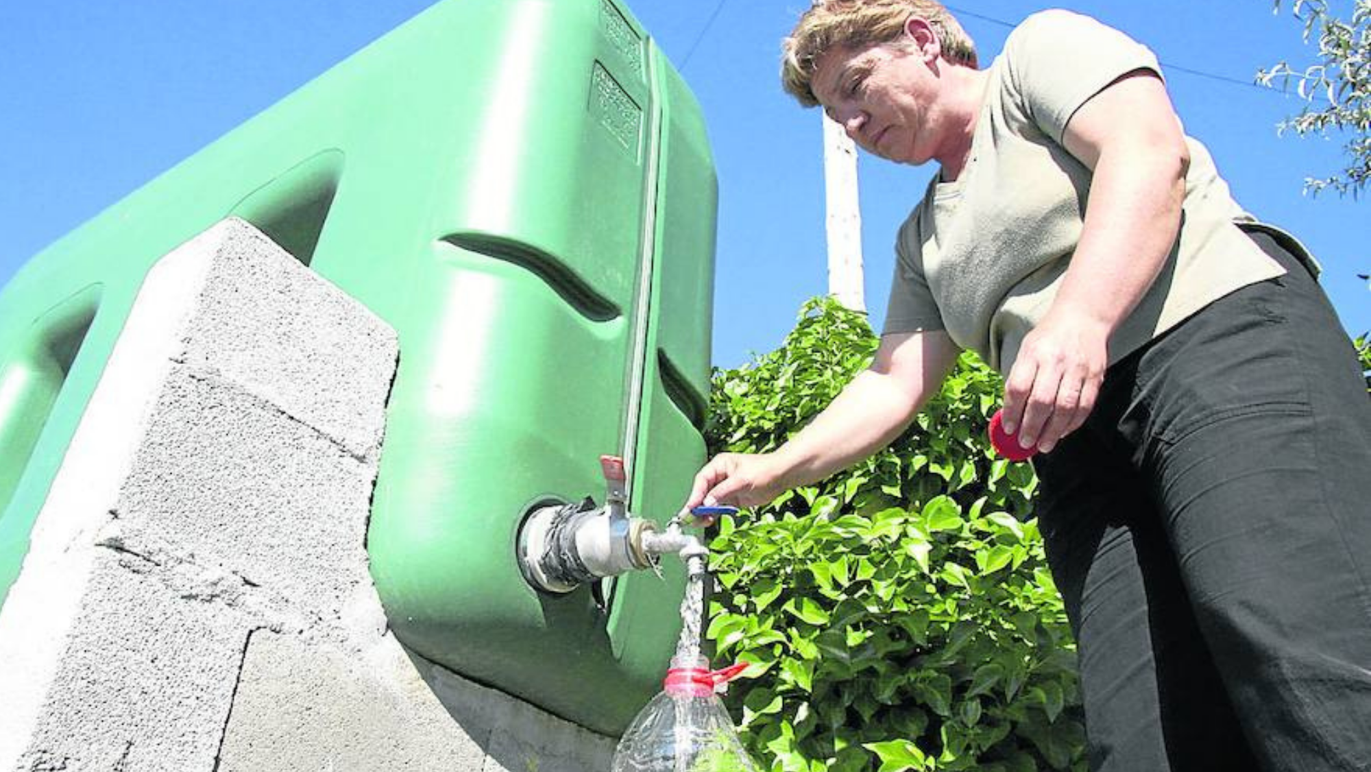Una mujer saca agua de un grifo, en una foto de archivo. / Carlos García (EFE)