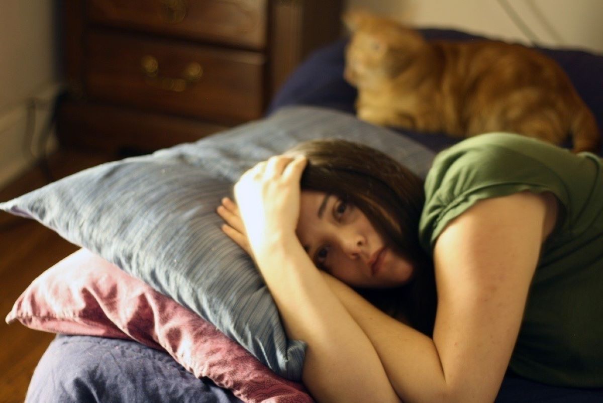 Una mujer acostada aquejada de dolor de cabeza / EP