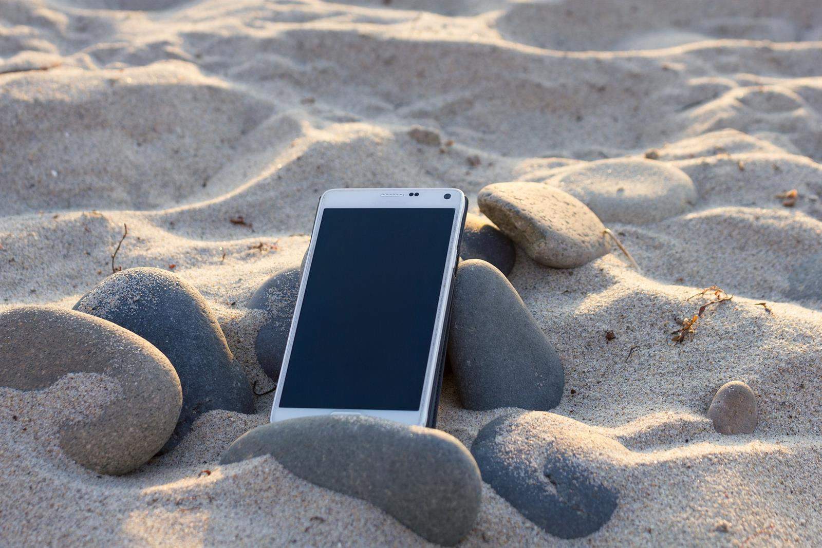 Un teléfono móvil en la arena de una playa: claves para la desconexión digital en vacaciones / EUROPA PRESS