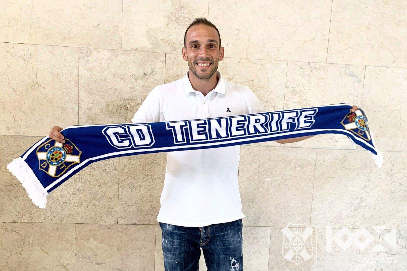 Nacho Martínez posa con la bufanda del CD Tenerife a su llegada al aeropuerto de Los Rodeos./ CDT