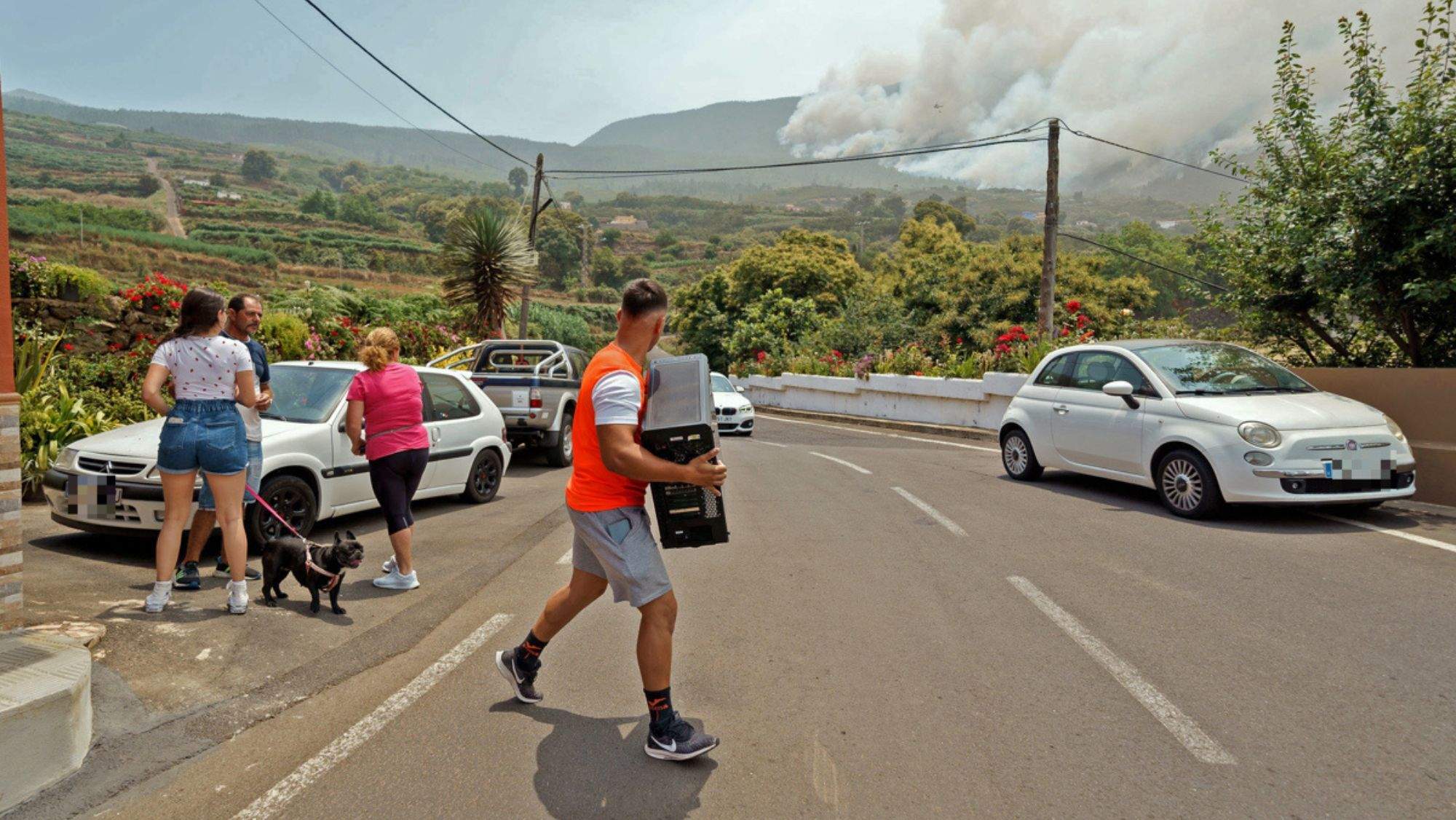 Vecinos evacúan sus viviendas ante el acercamiento del incendio. / Efe