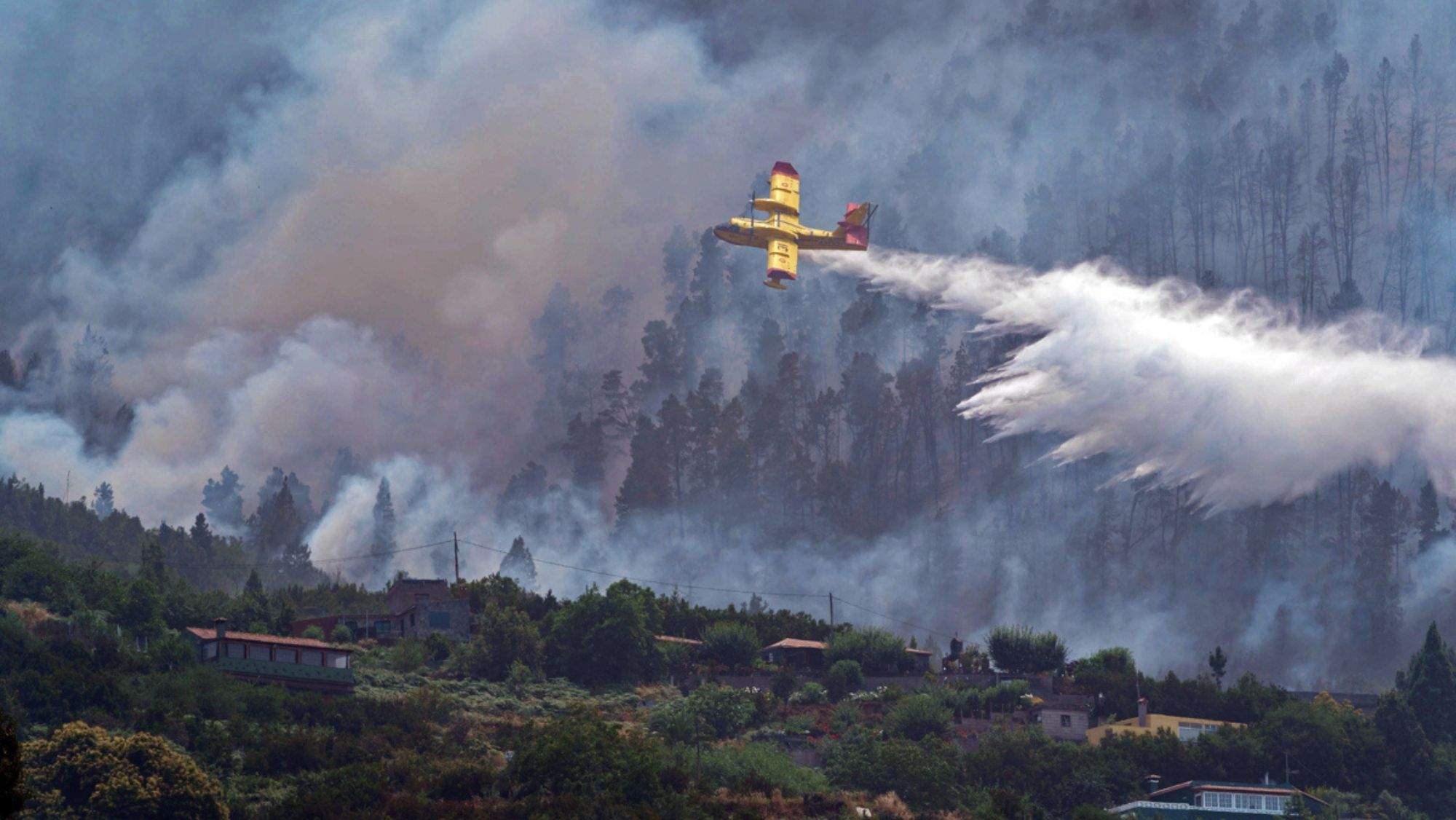 Un hidroavión realiza una descarga sobre el incendio forestal . / Efe
