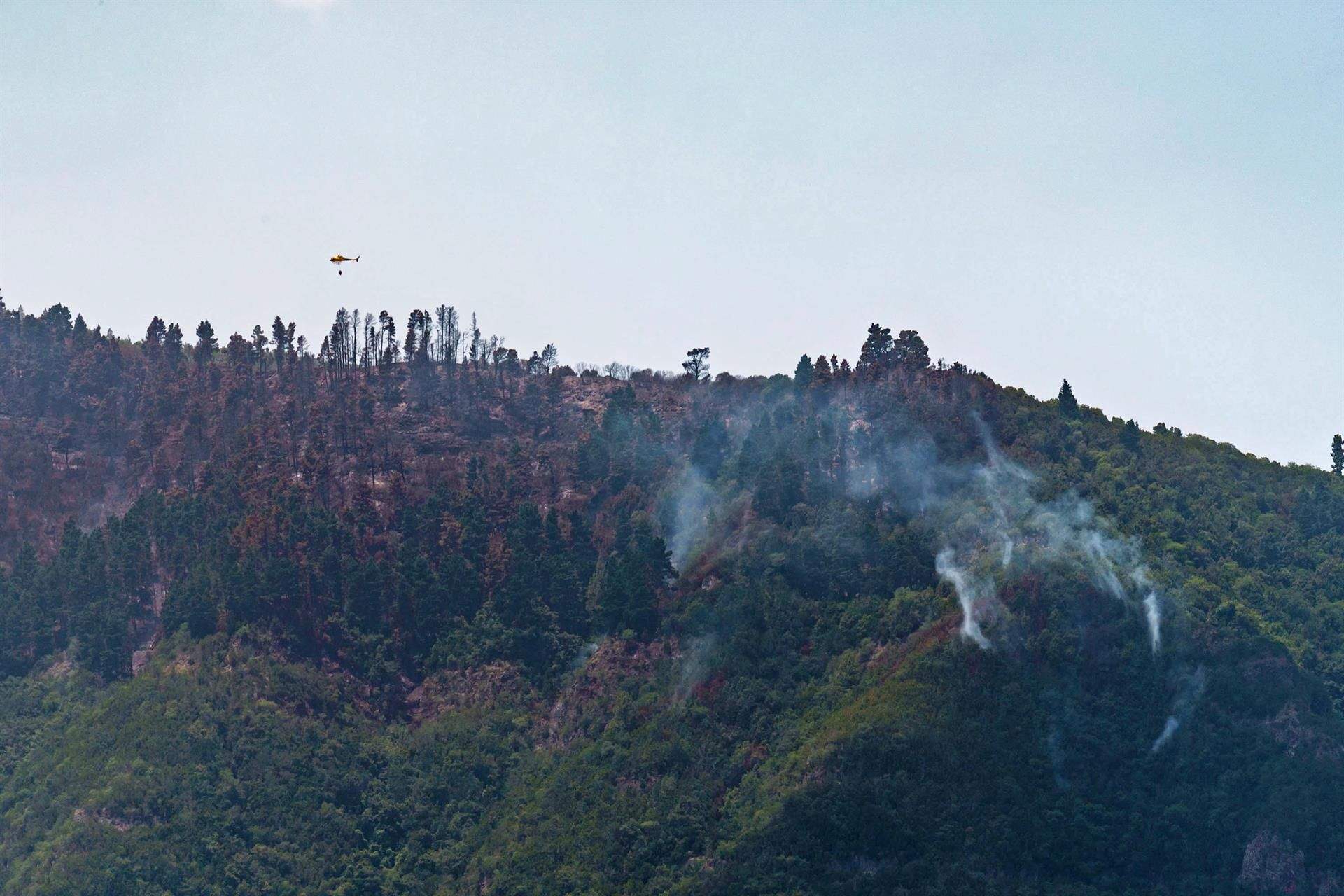 Uno de los helicópteros que participa en el operativo de extinción del incendio sobrevuela las llamas/. EFE/ Ramón De La Rocha
