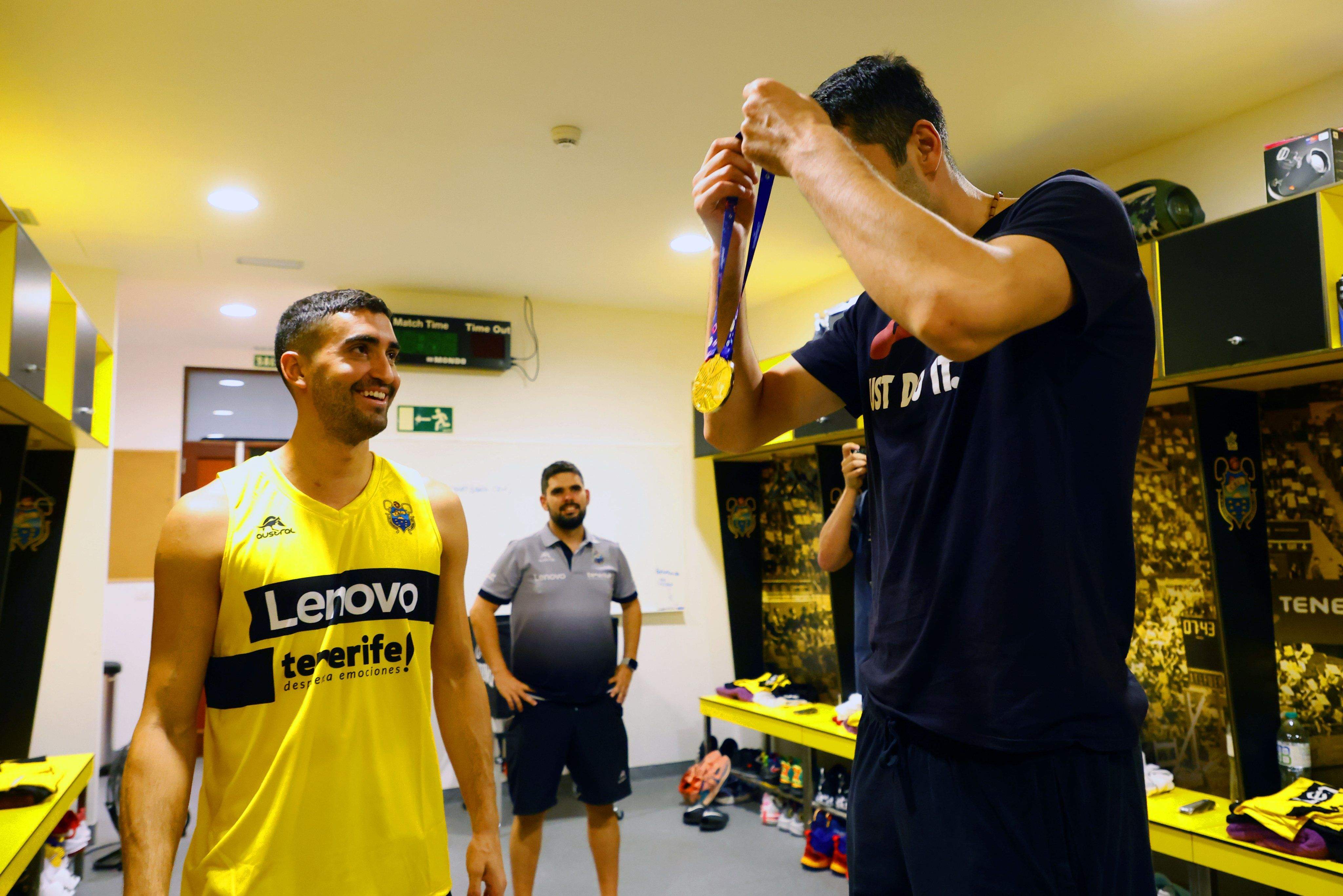 Jaime Fernández le presta su medalla de oro a Shermadini en los vestuarios del Santiago Martín./ CBC.