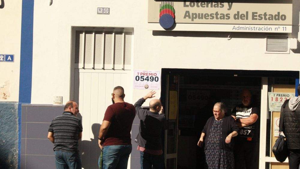 Alberto Pérez de Lucía, de la administración de la avenida Trinidad, cuelga el cartel de primer premio en la fachada./ Álvaro Oliver (AH)