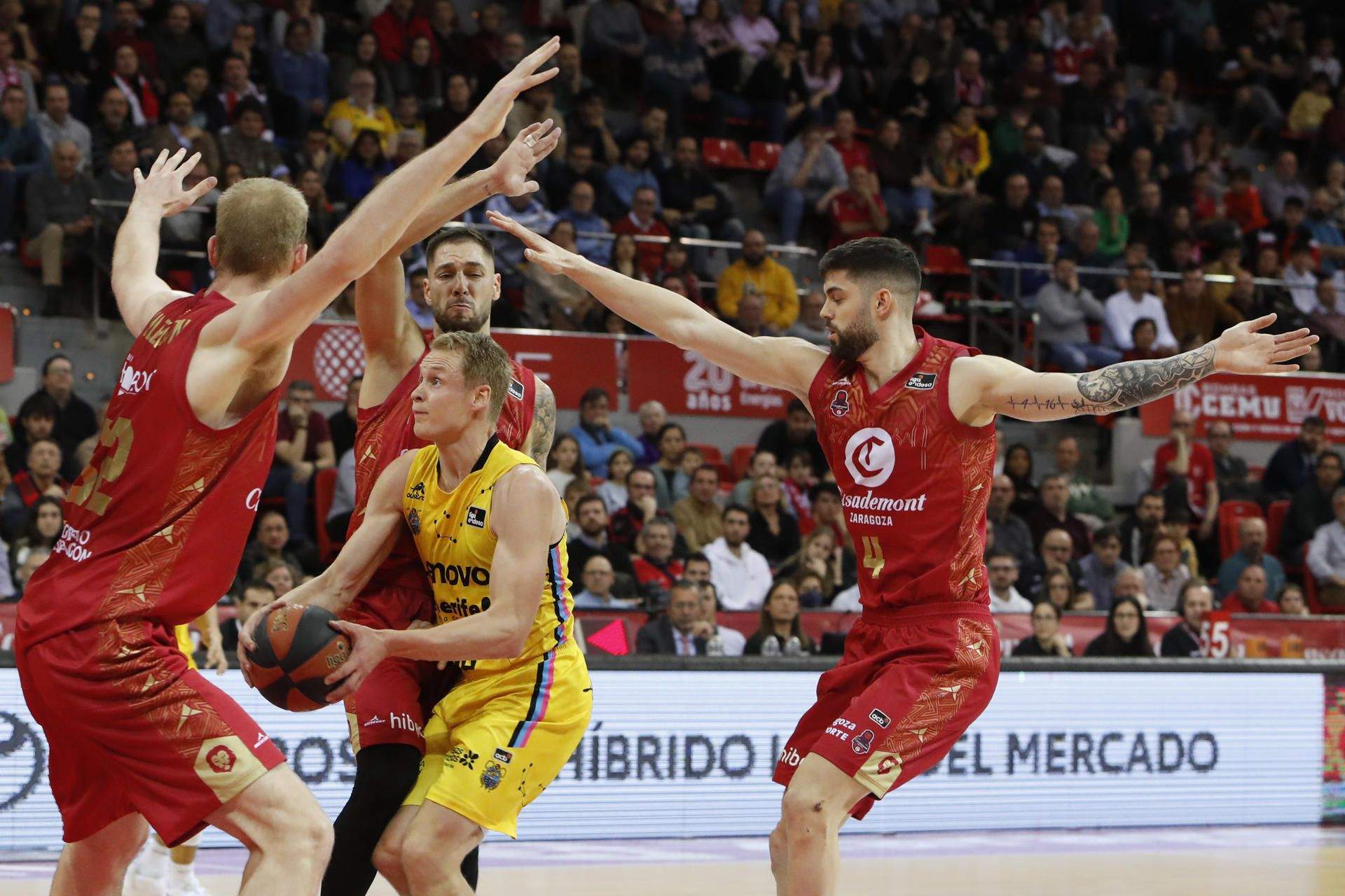 Salin, rodeado de jugadores de Casademont Zaragoza en la victoria del Canarias por 83-87 en el Pabellón Príncipe Felipe./ EFE.