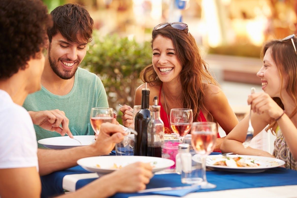 Imagen de archivo de una familia comiendo en una terraza / Canva