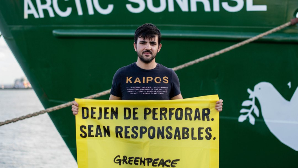 Alejandro, un activista de Greenpeace, sostiene una pancarta dirigida a Shell para que cese las perforaciones./ Greenpeace