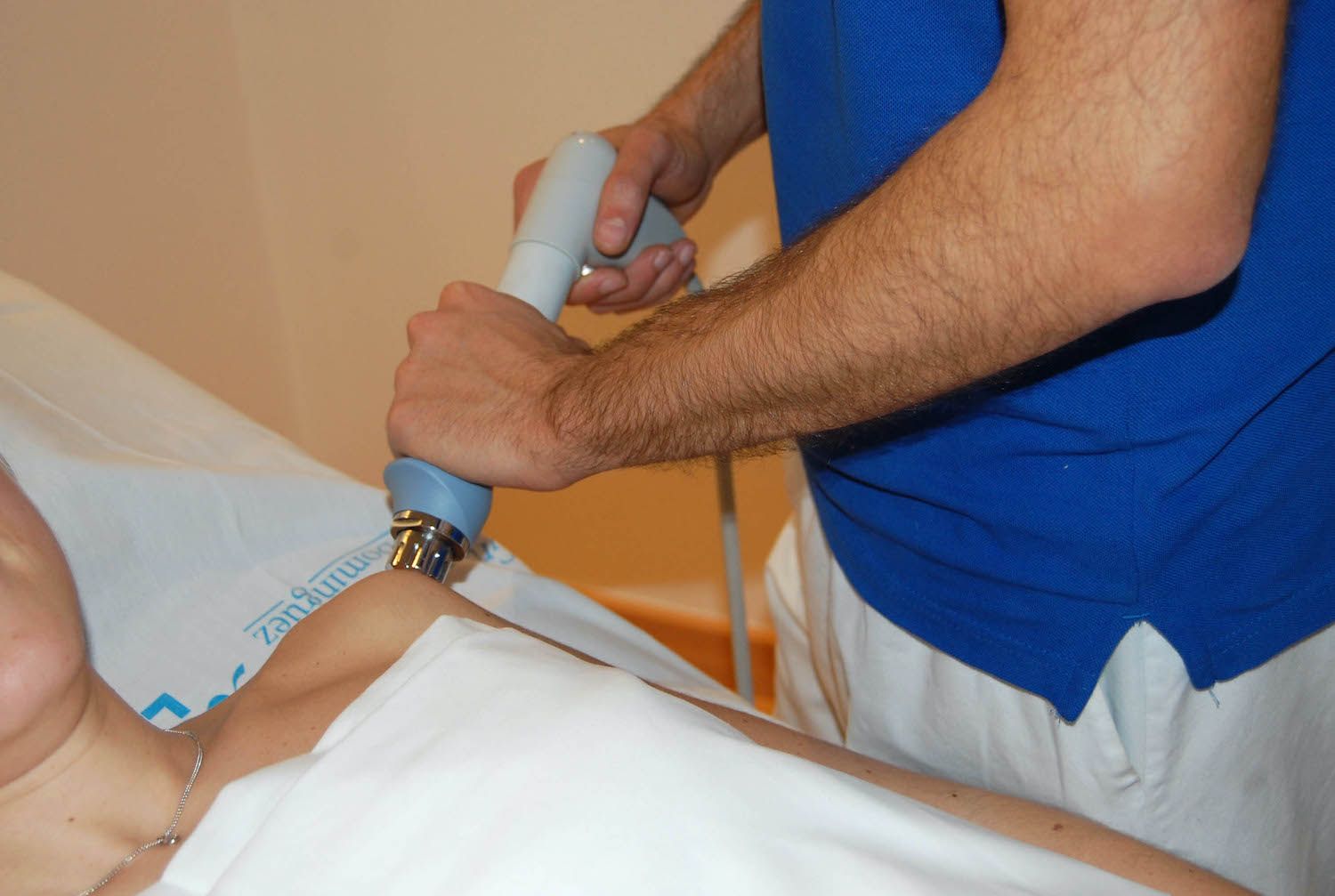 Un fisioterapeuta aplica onda de choque en el hombro de un paciente / QUIRÓNSALUD