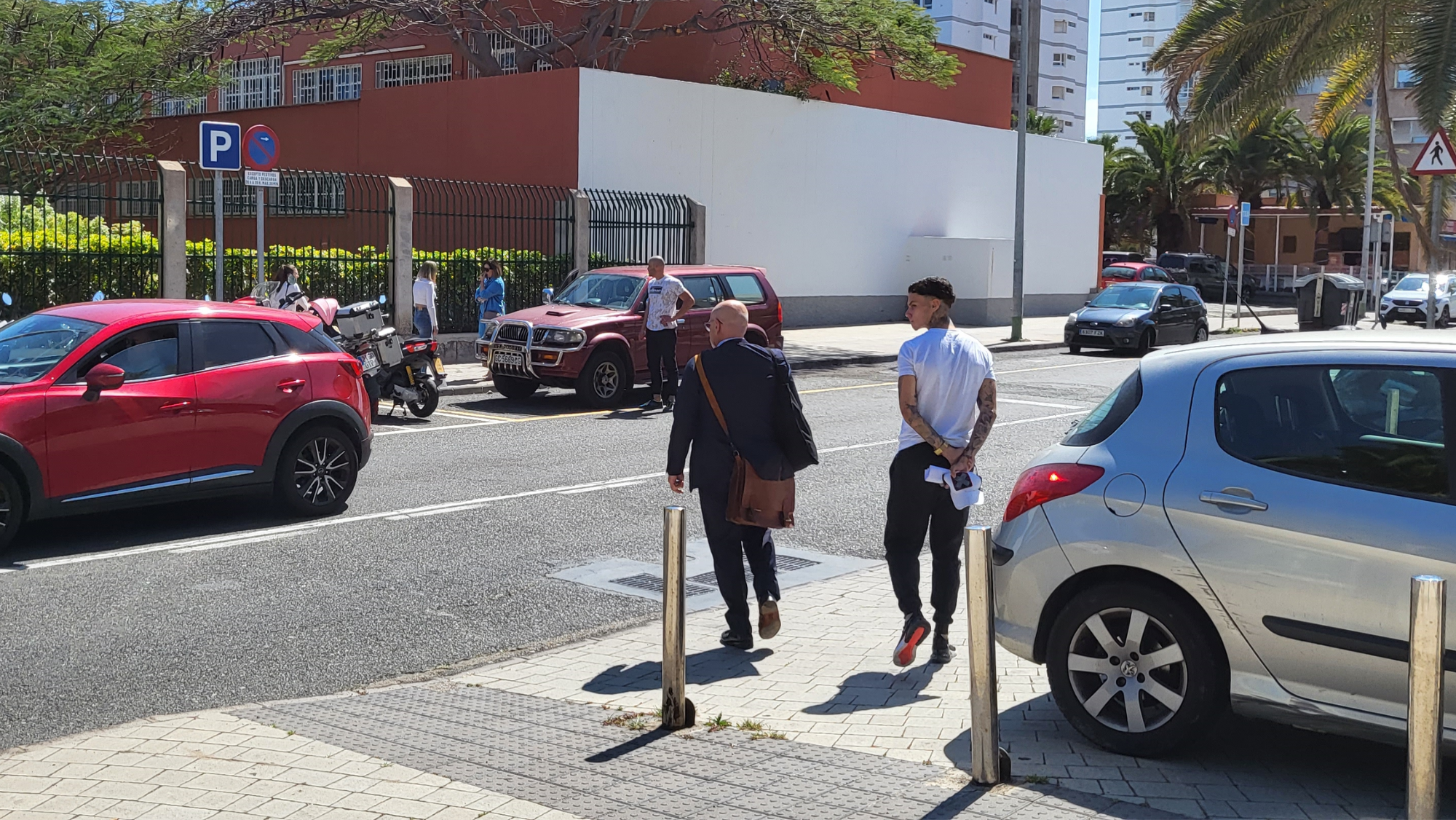 Joel Domínguez (i), saliendo de los juzgados junto a su abogado (d), al fondo  lo esperaba su familia y su representante. / AH