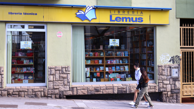 Dos jóvenes miran el escaparate de la librería Lemus en la avenida Trinidad 