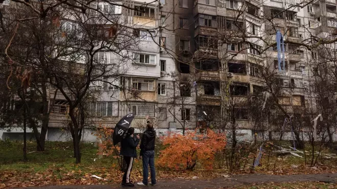 Ucranianos delante de un edificio dañado por bombas rusas en Jersón. /EFE