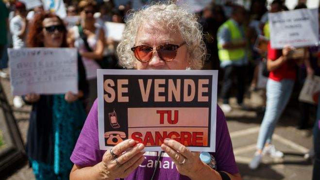 Una mujer porta un cartel en contra de la privatización del Banco de Sangre Una mujer porta un cartel en contra de la privatización del Banco de Sangre