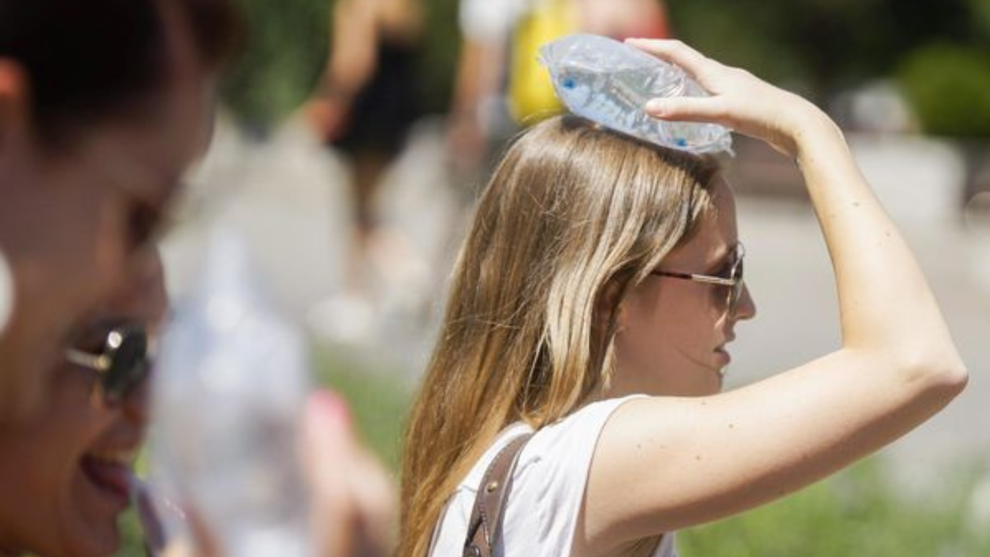 Una mujer se pone una bolsa de hielo en la cabeza para soportar las altas temperaturas. /EFE