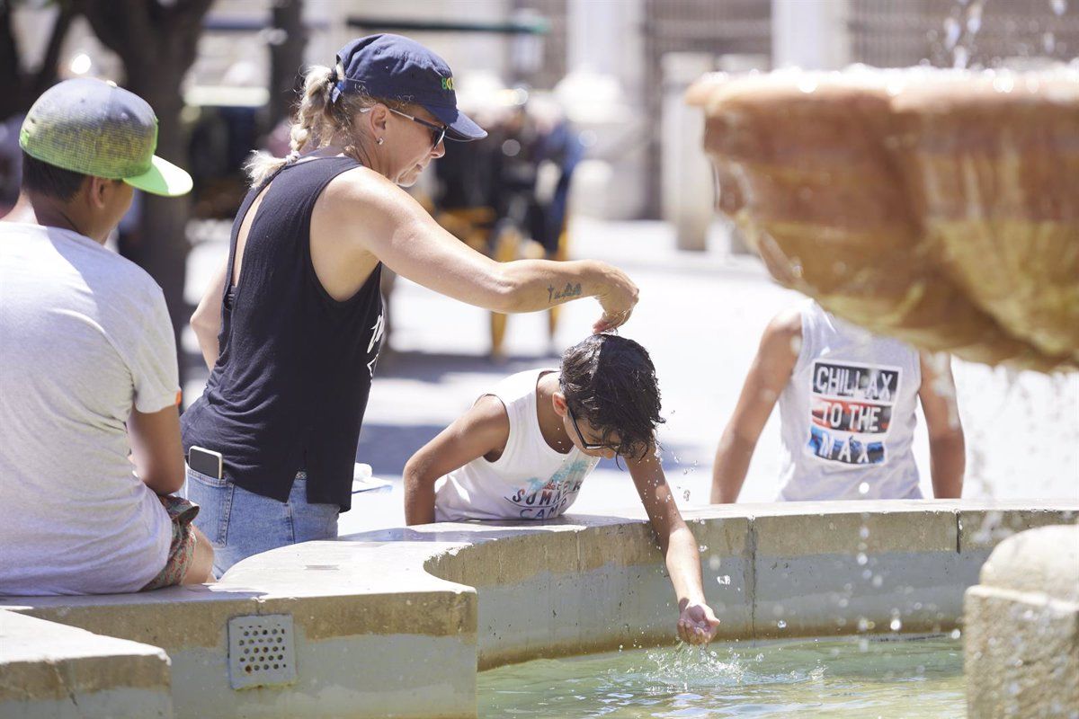 Una mujer echando agua a un niño para contrarrestar el ambiente caluroso. / EUROPA PRESS 