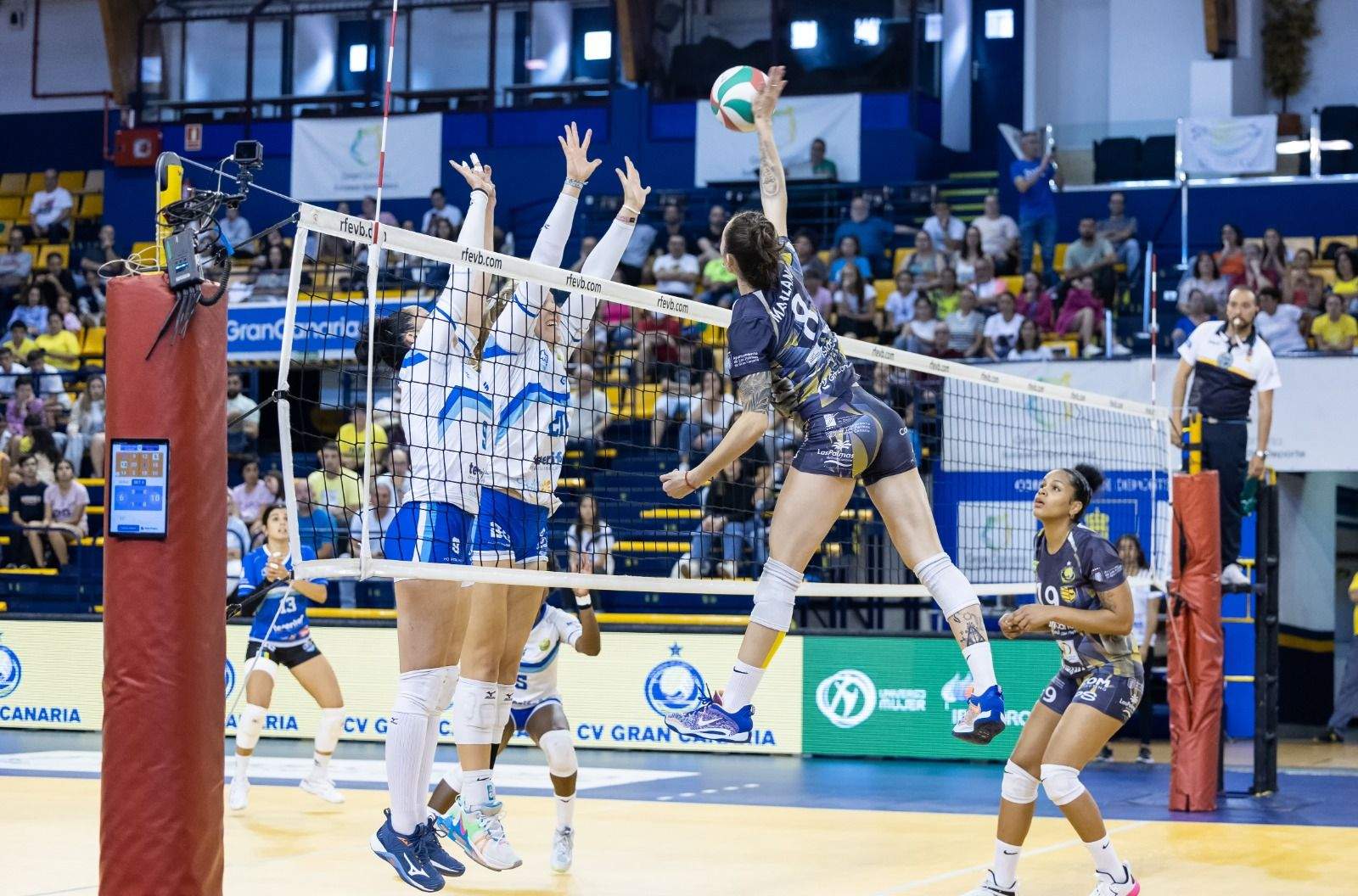 Saray Manzano remate ante el bloqueo de Aranda y Wolocwiz en la victoria del Olímpico de Gran Canaria frente al Haris./ CV HARIS.