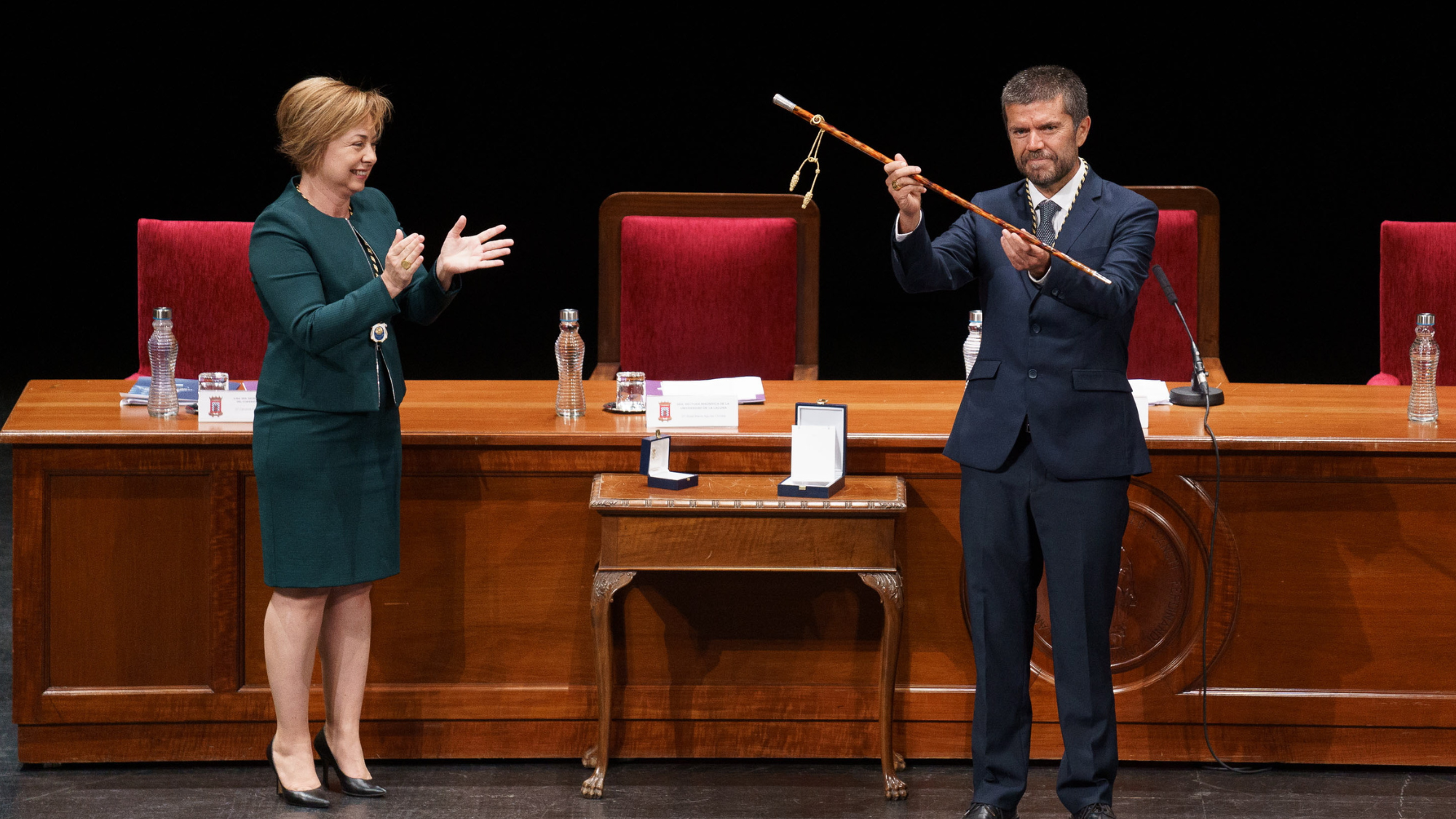 El nuevo rector de la Universidad de La Laguna, Francisco García (d), recibe el bastón que simboliza su cargo durante el acto de su toma de posesión, en presencia de su antecesora, Rosa Aguilar. / RAMÓN DE LA ROCHA-EFE 