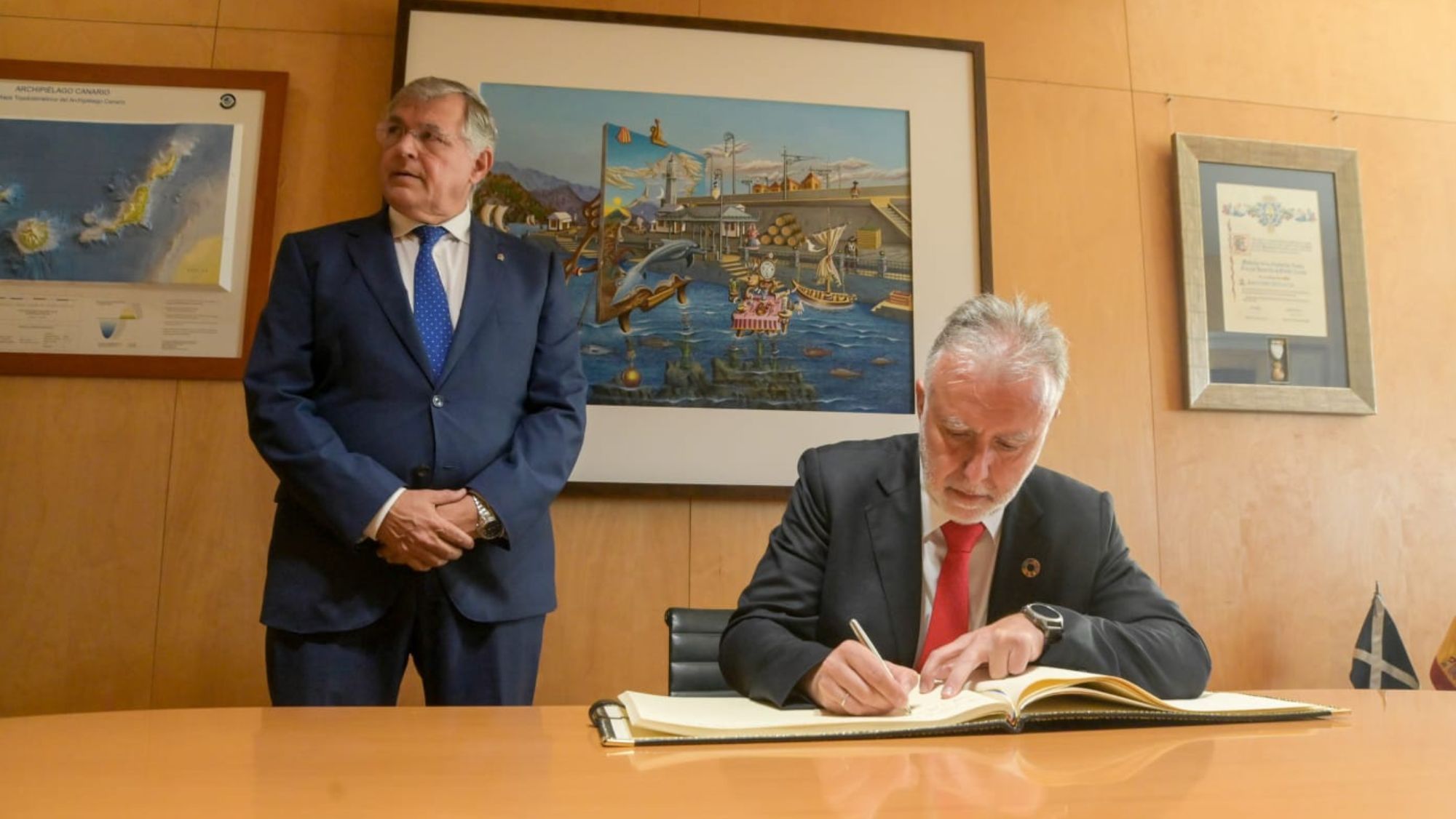 El presidente de Canarias, Ángel Víctor Torres, firma unos documentos, con Carlos González, presidente de la Autoridad Portuaria, a su espalda. / CEDIDA