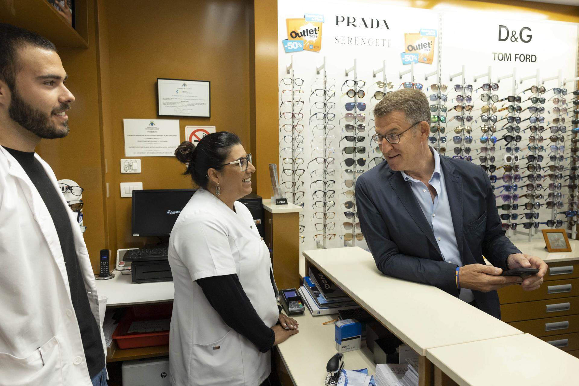 El presidente del Partido Popular, Alberto Núñez Feijóo, conversa con la empleada de una óptica durante su visita a La Laguna, en Tenerife./ EFE - MIGUEL BARRETO