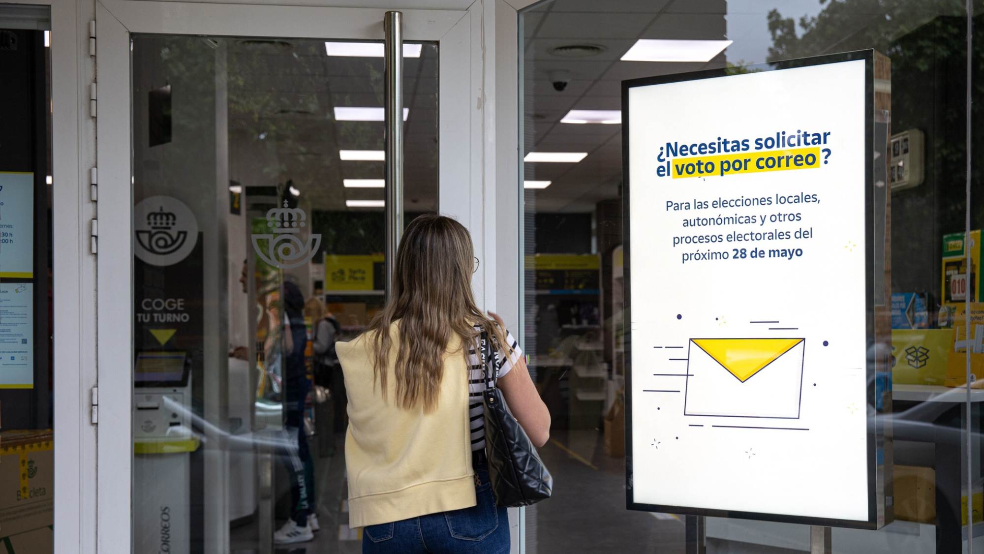 Una mujer entra en una oficina de Correos para tramitar su voto por correo./ CEDIDA