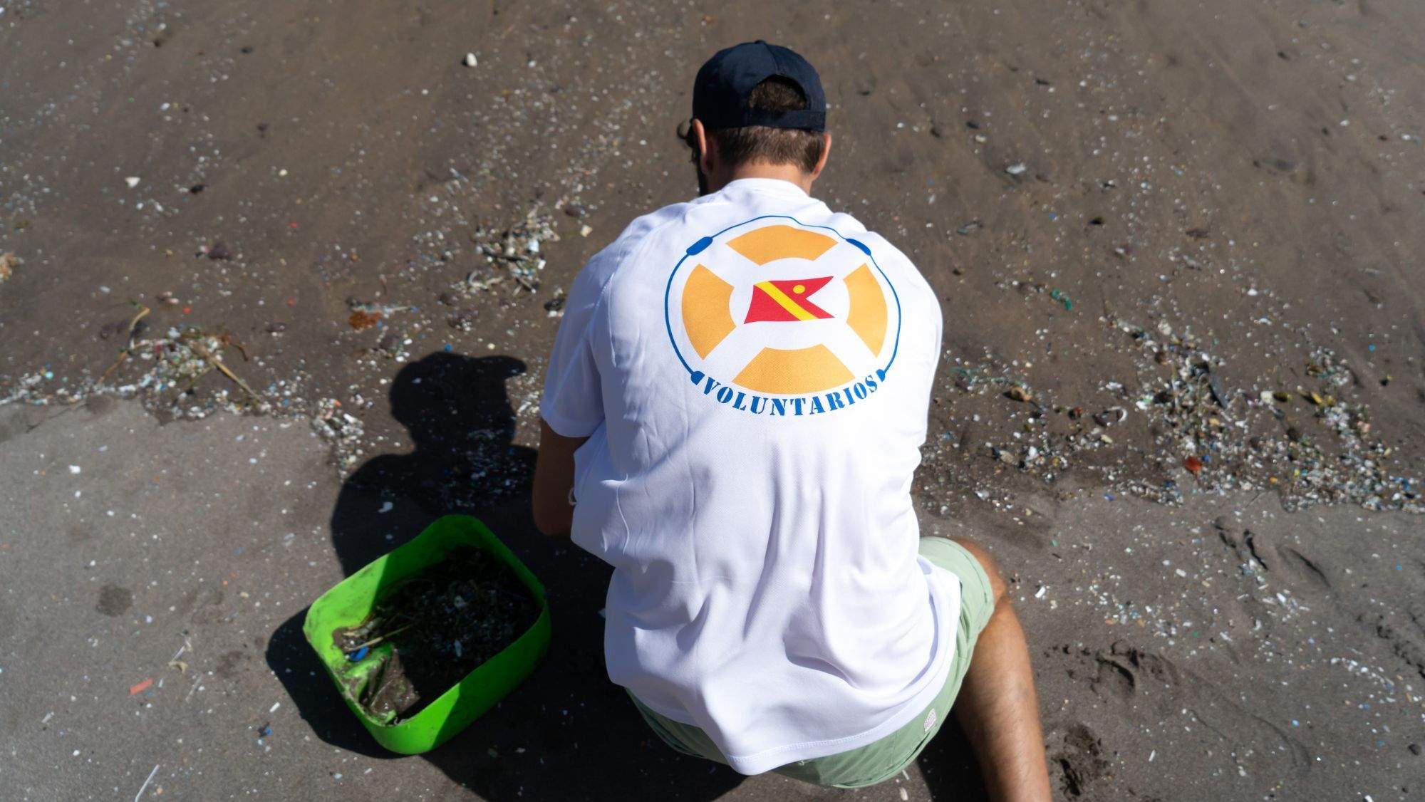 Un voluntario con una camiseta de Fred. Olsen limpiando el litoral / CEDIDA