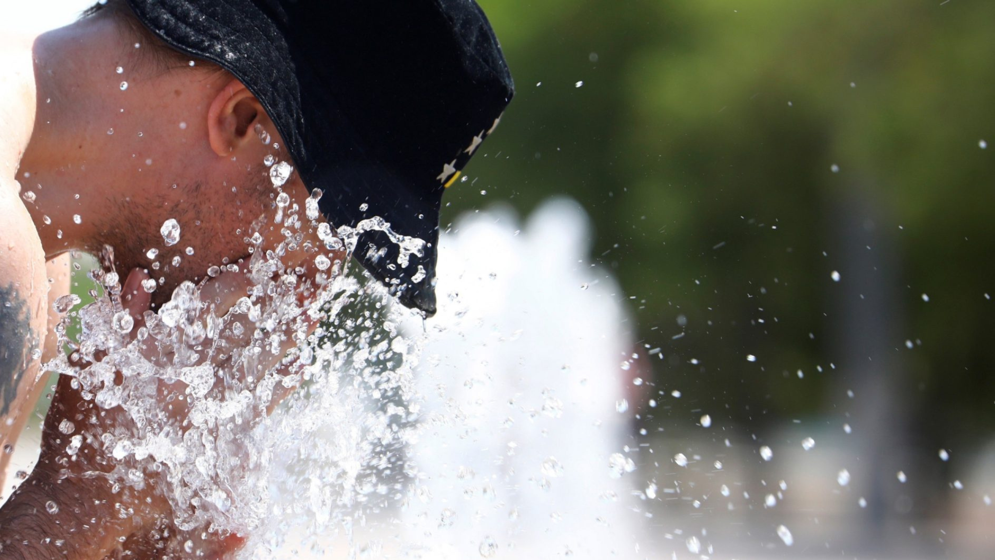 Un hombre se refresca en una fuente por las altas temperaturas, siendo julio el mes más cálido / EFE