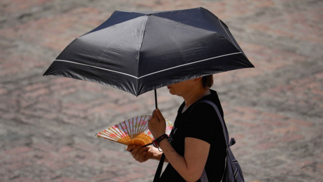 Una mujer protegiéndose de la alerta por temperaturas con un paraguas / EFE