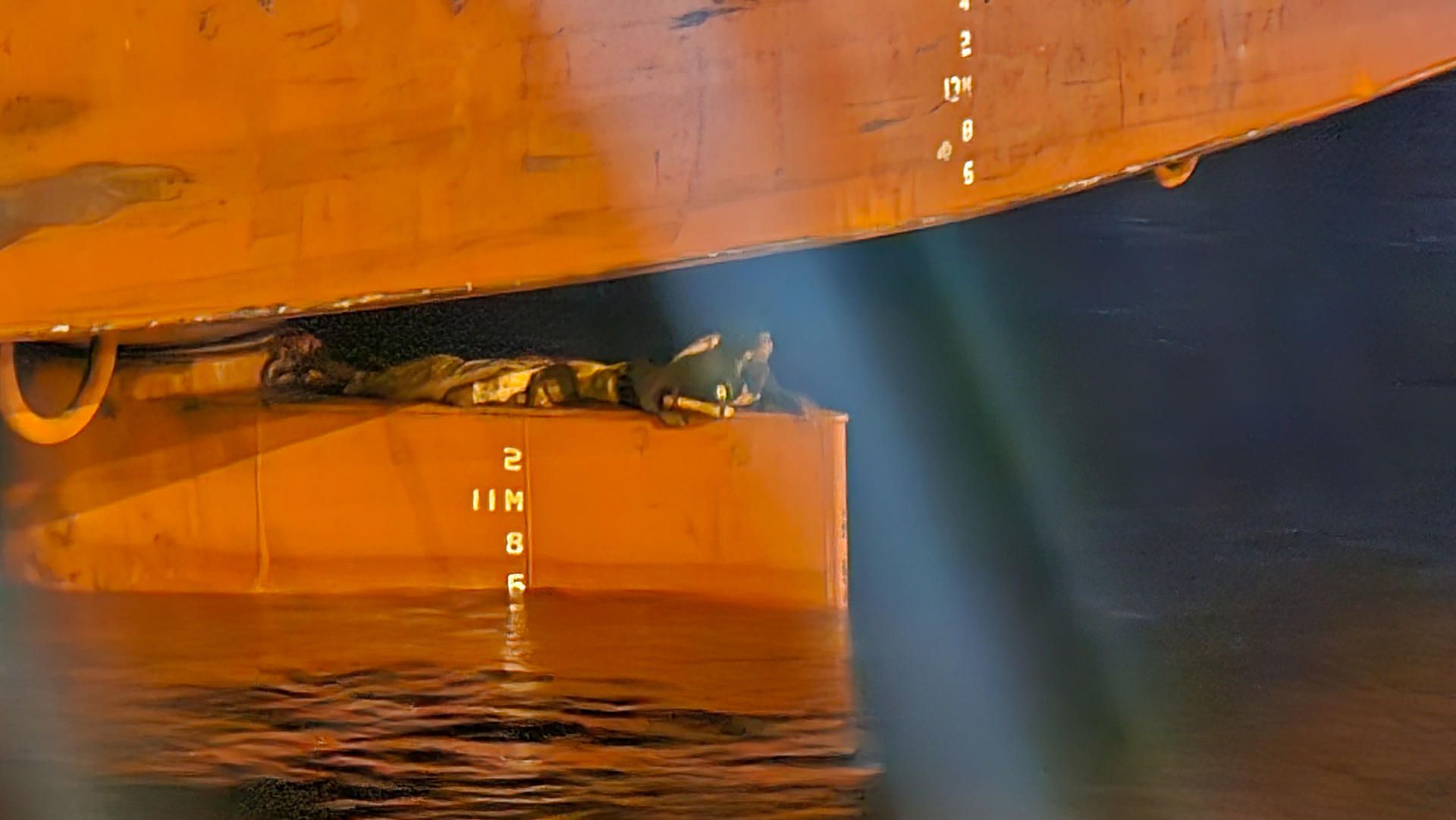 Los dos jóvenes bajo el MSC Marta. / EFE - IRIOME MARCIAL MORENO