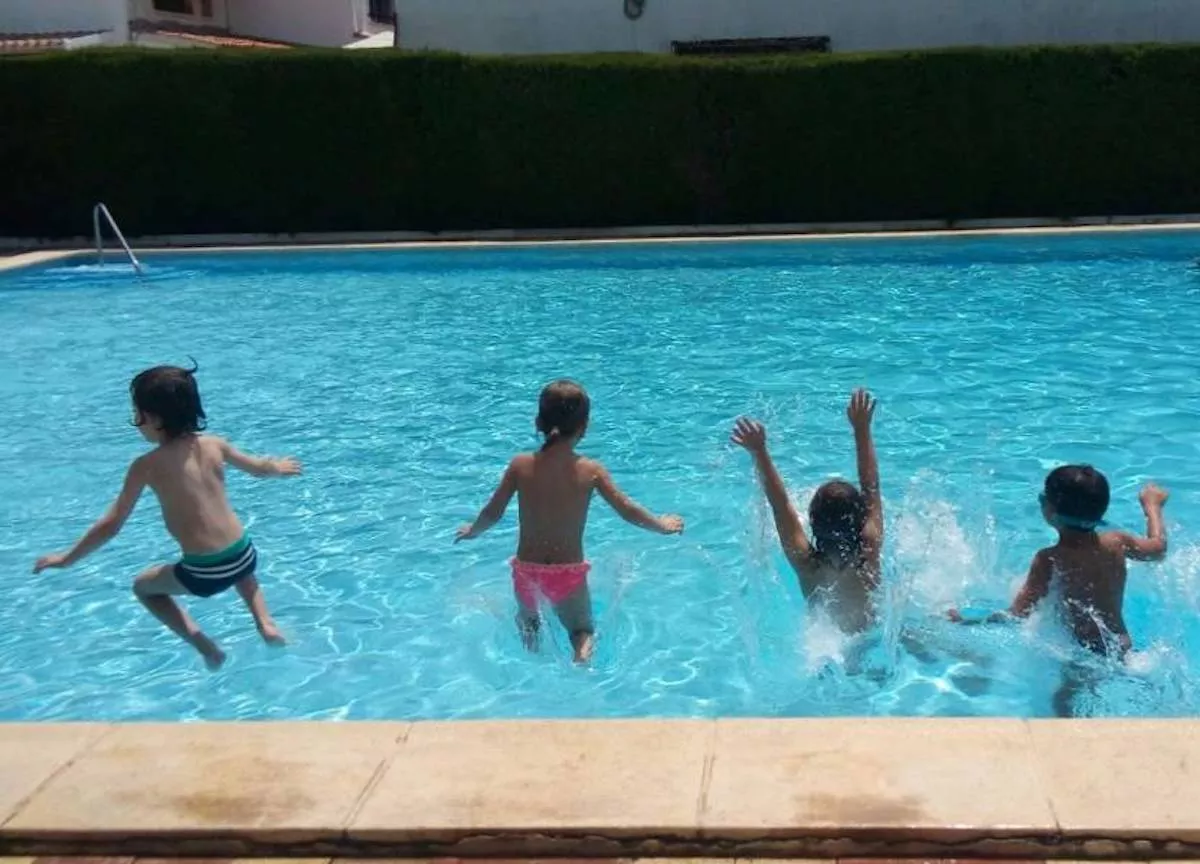 Un grupo de niños salta a la piscina para bañarse / QUIRÓNSALUD