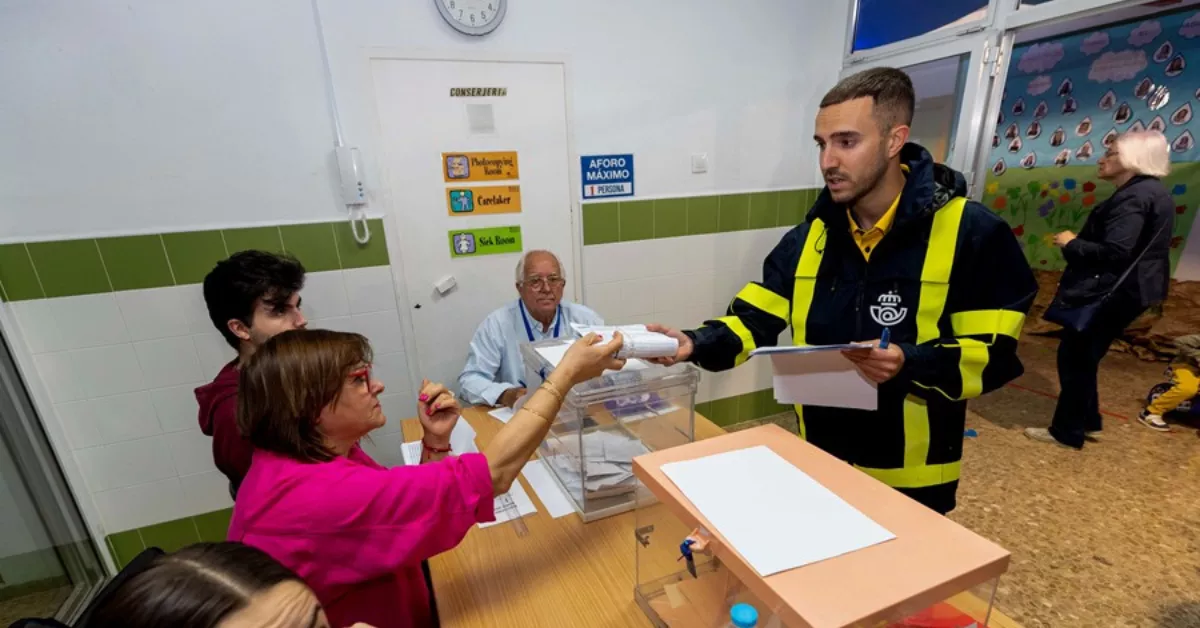 Un cartero entrega a la presidenta de una mesa electoral el voto por correo / EFE