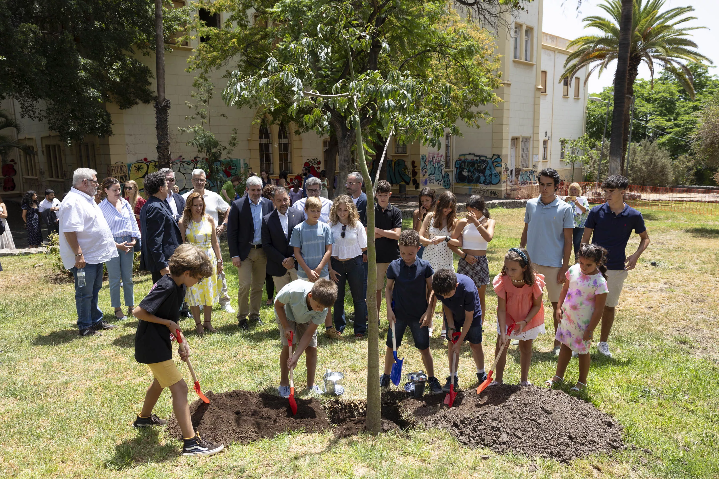 Varios niños plantan un árbol en el parque Viera y Clavijo mientras varios representantes institucionales miran. / EFE-MIGUEL BARRETO