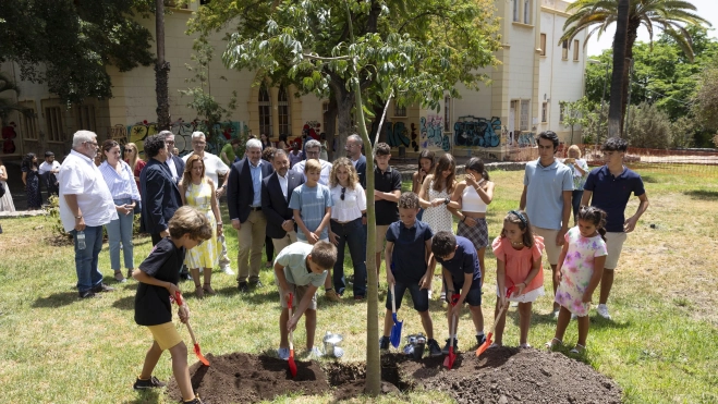 Varios niños plantan un árbol en el parque Viera y Clavijo mientras varios representantes institucionales miran. / EFE-MIGUEL BARRETO