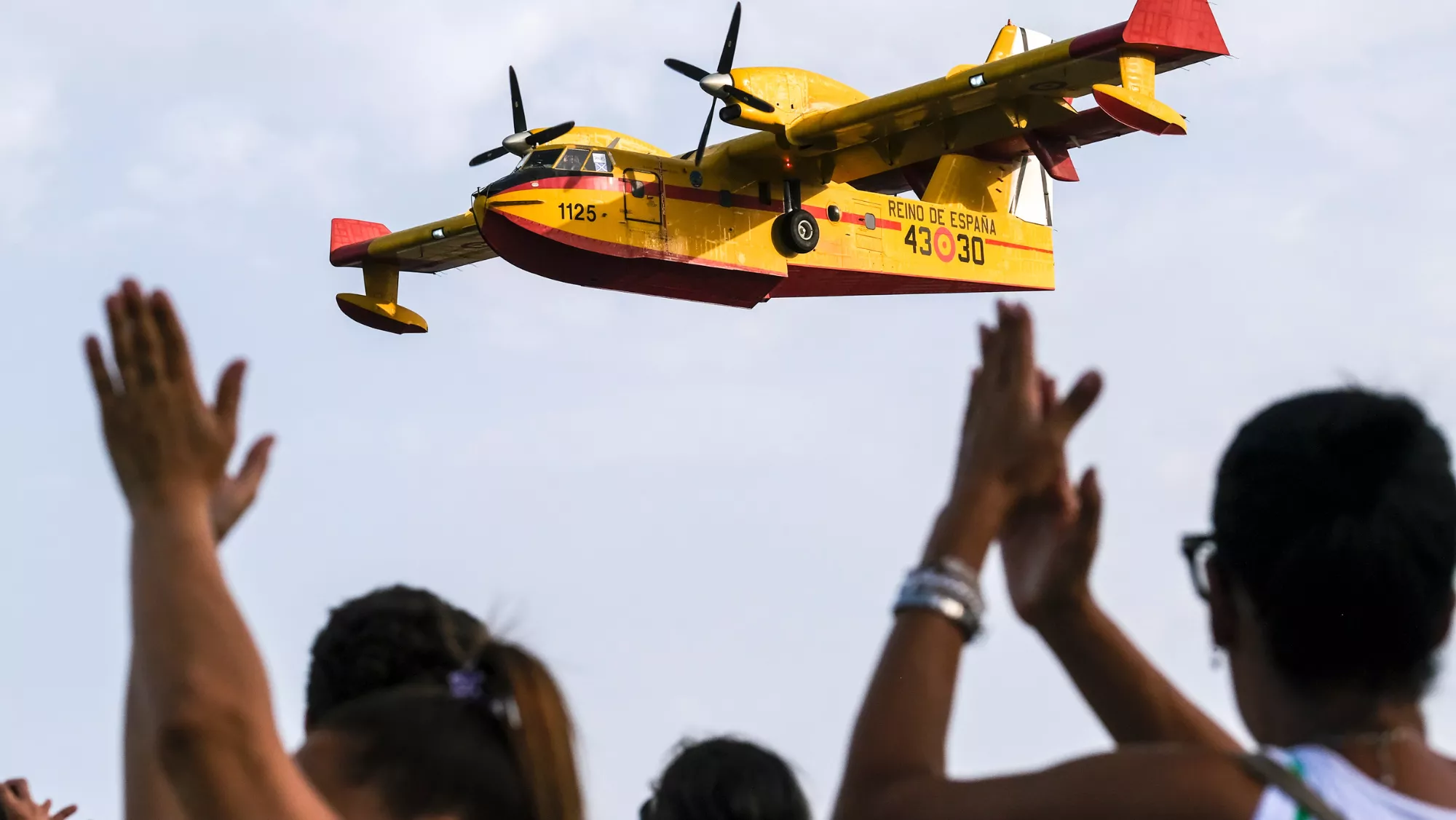 Personas celebran el trabajo de un hidroavión que trabaja en el incendio / EFE - ALBERTO VALDÉS