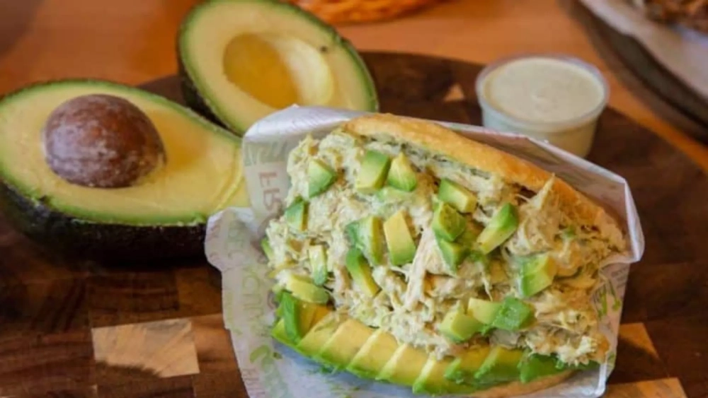 Una arepa 'reina pepiada' con aguacates de fondo./ ARCHIVO