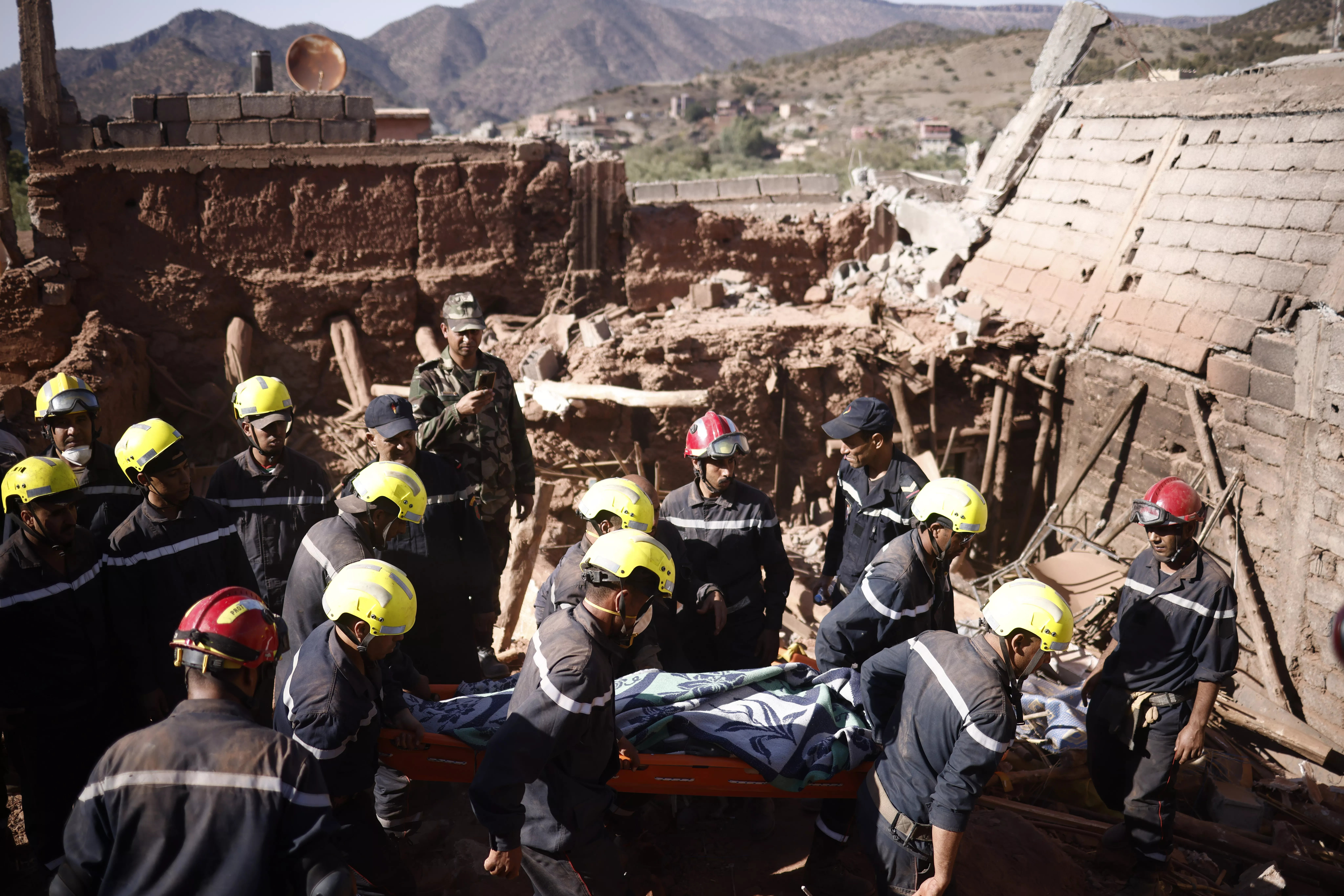 Un grupo de bomberos rescata de los escombros el cuerpo de una persona fallecida en Ouirgane (Marruecos) tras el terremoto que sacudió el país este sábado. / YOAN VALAT-EFE