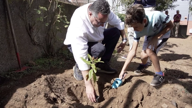 El consejero Poli Suárez planta un árbol junto a un niño / CEDIDA
