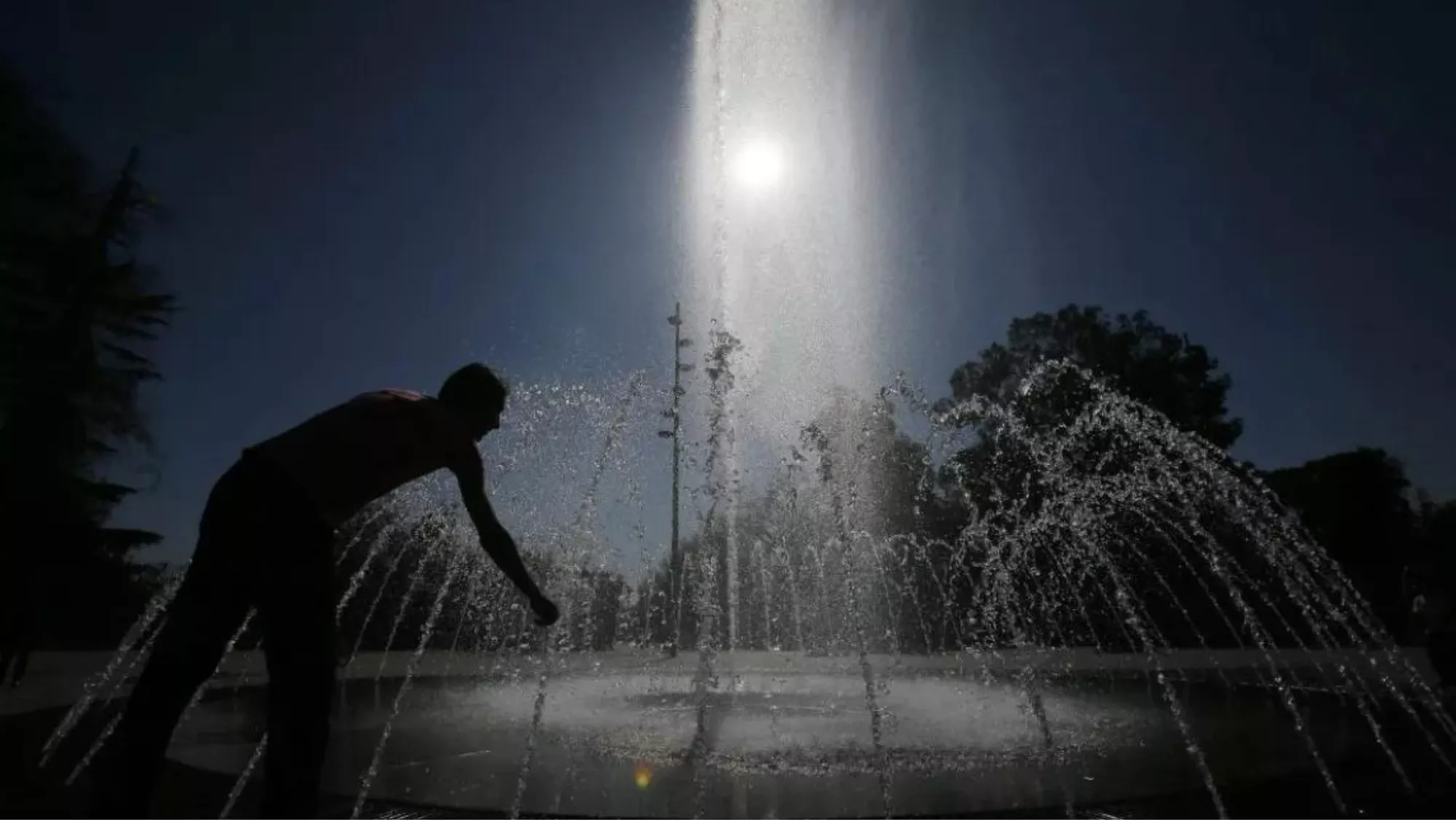 Un hombre se refresca en una fuente por la noche / EFE - MARIO RUIZ