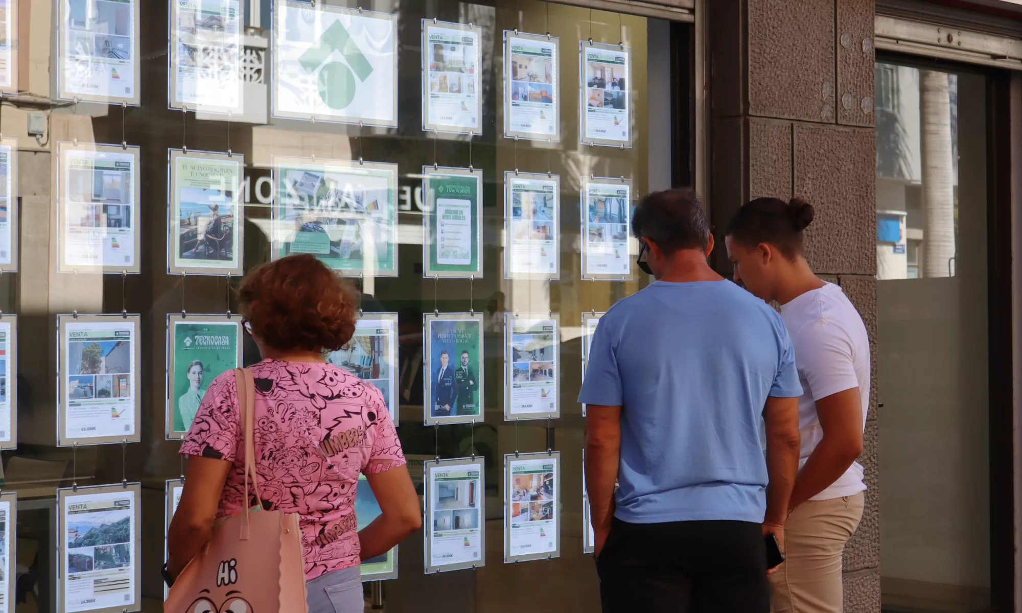 Tres personas miran un escaparate con información sobre viviendas en Canarias . / ATLÁNTICO HOY