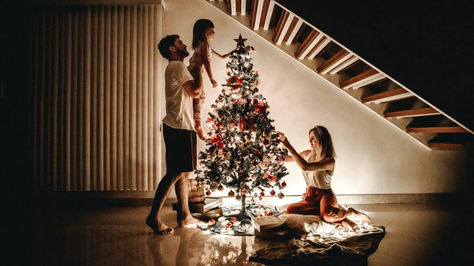 Una familia coloca los adornos de Navidad en el árbol / UNSPLASH