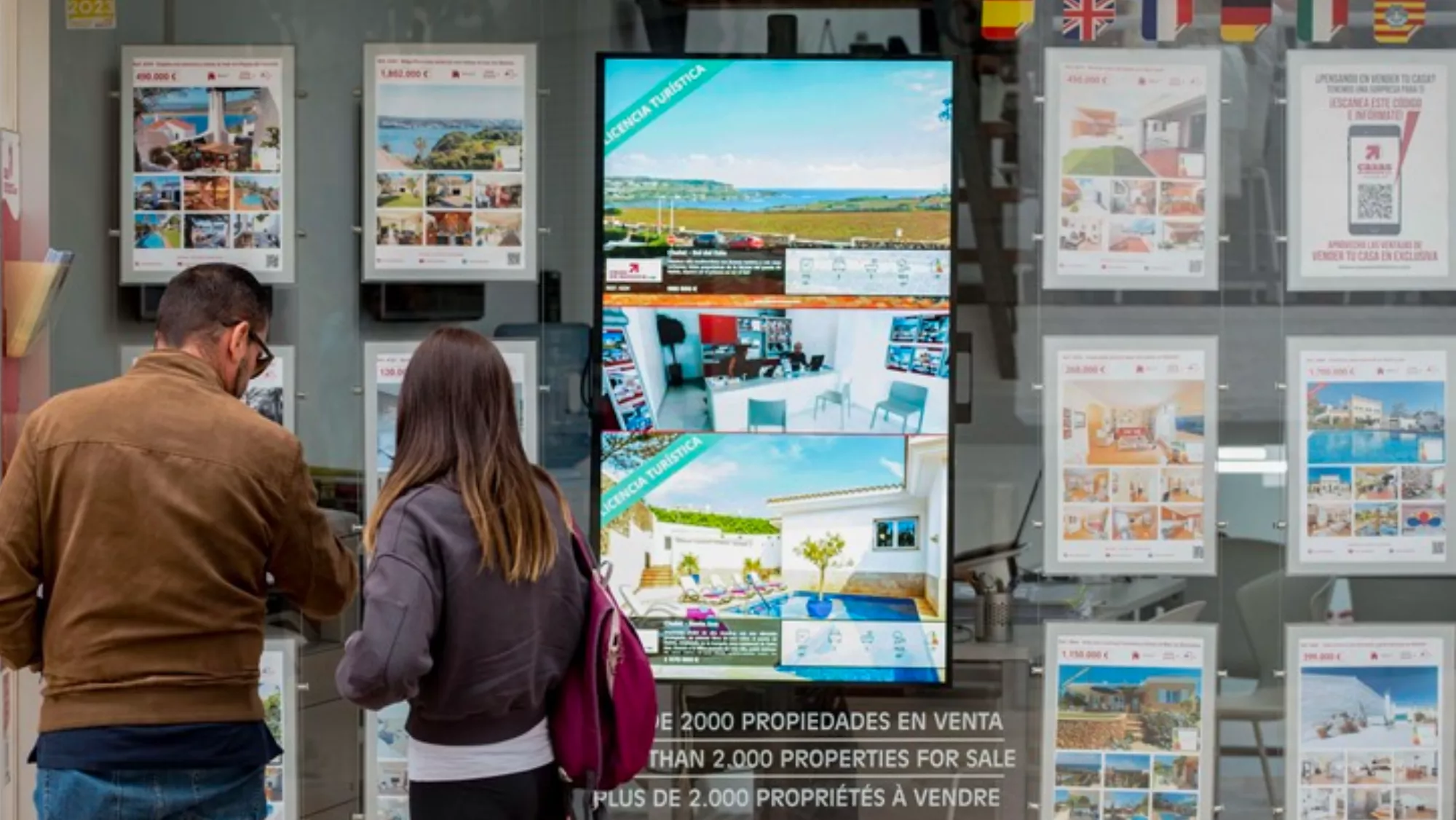 Dos personas viendo carteles de viviendas en venta / EFE