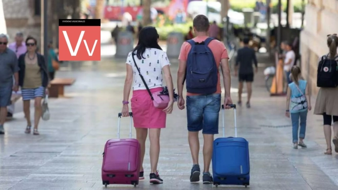 Dos turistas se dirigen a su destino tras pasar sus vacaciones en una vivienda vacacional. / EFE