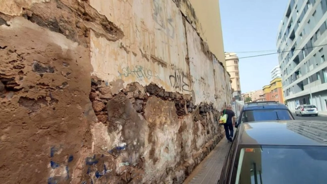 Persona pasando por la acera donde caen piedras del muro deteriorado / ATLÁNTICO HOY
