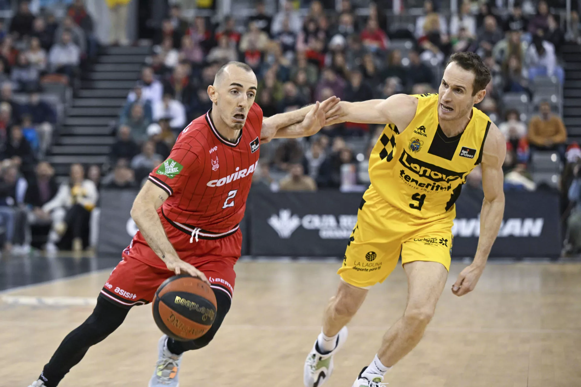 El base de Covirán Granada Jonathan Roussellie (i) controla la pelota ante Marcelinho Huertas (d), del Lenovo Tenerife / EFE / Miguel Ángel Molina