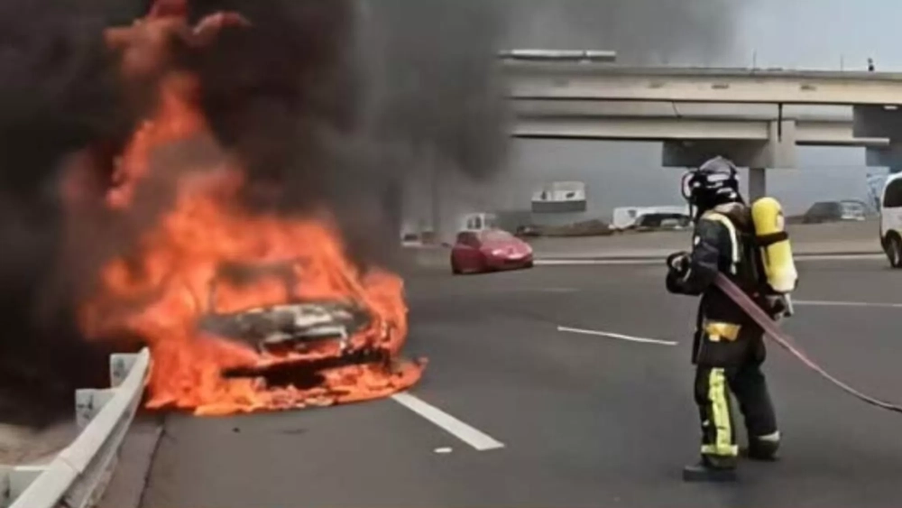 Un bombero apaga un incendio en un coche en la TF-5 a la altura del Hospital de la Candelaria en 2023./ ARCHIVO